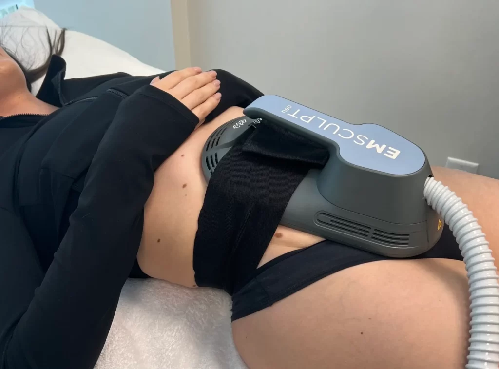 Mujer recibiendo tratamiento Emsculpt Neo en abdomen durante sesión estética.